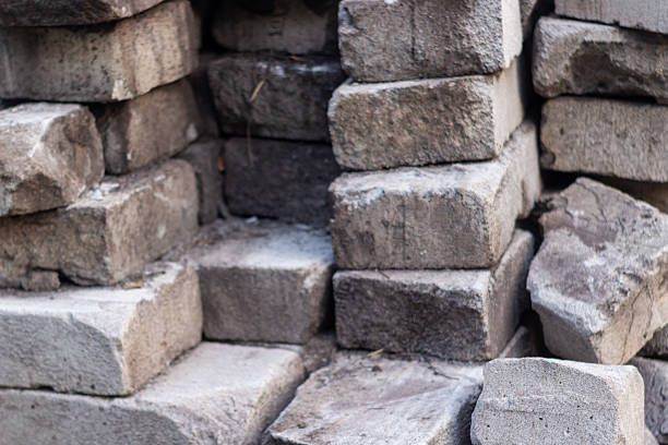 A detailed shot showcases a stack of weathered stone bricks, highlighting their varied textures and natural earthy tones. Ideal for backgrounds or designs related to construction or geology.
