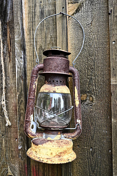 istock Old rusty lantern with glass chamber hanging on a weathered wooden wall. 2229429724