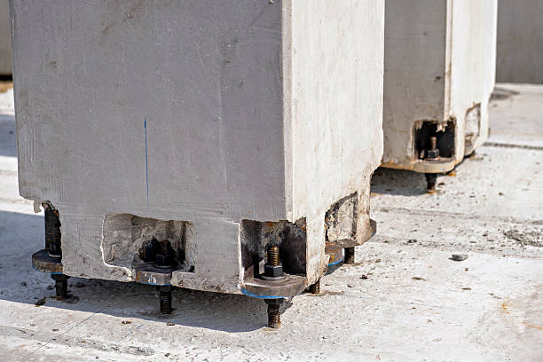 Vintage retro old broken cracked concrete electrical utility pole with rusted metal holders for white ceramic insulators disconnected from electrical grid on clear blue sky background