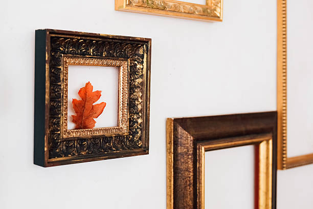 Decorative wall with framed autumn leaf among ornate frames in a cozy interior setting