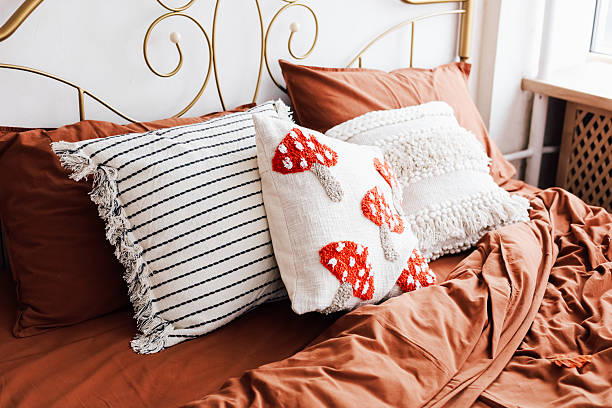 istock Cozy bedroom setting with decorative pillows on a warm toned bedspread 2229431116