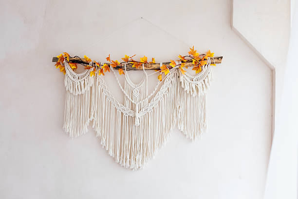 Macrame wall hanging with autumn leaves displayed in a minimalist interior setting