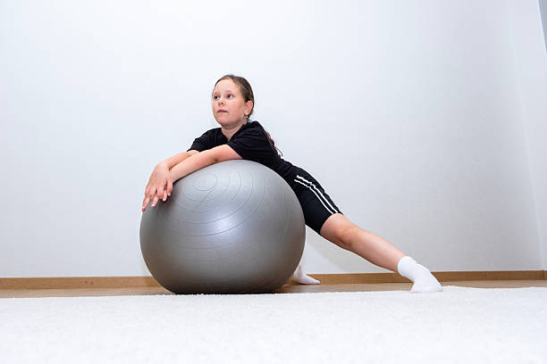 istock Caucasian girl, 10 years old, doing exercises, using exercise ball. 2229435305
