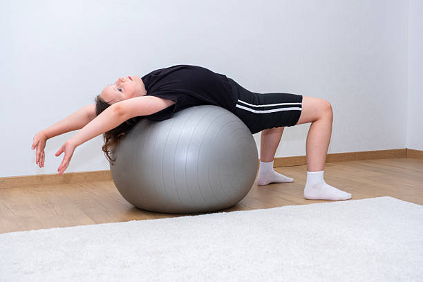 istock Caucasian girl, 10 years old, doing abdominal exercises, using exercise ball. 2229435355