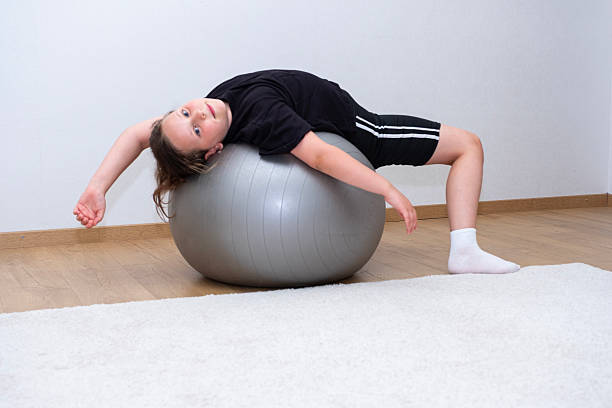 istock Caucasian girl, 10 years old, doing abdominal exercises, using exercise ball. 2229435358