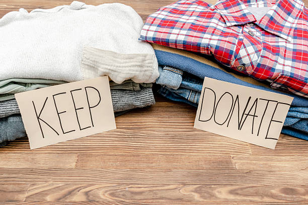 istock Stack of old baby children clothes sorted into Keep and Donate categories.Donation,volunteering help,humanitarian aid.charity on wooden background still life.Recycle clothing,eco cotton 2229435625