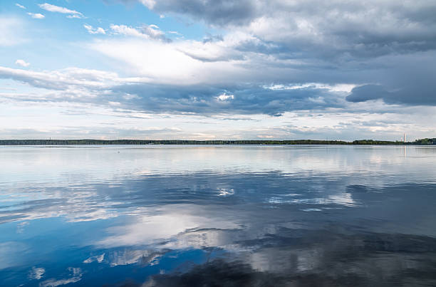 Blue lake with cloudy sky, natural background. Lake with forest on the shores at summer