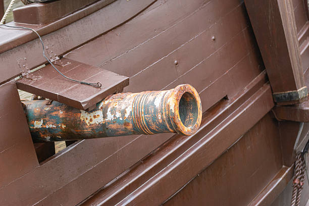 The ships cannon is secured with ropes on the deck of an old wooden sailboat.