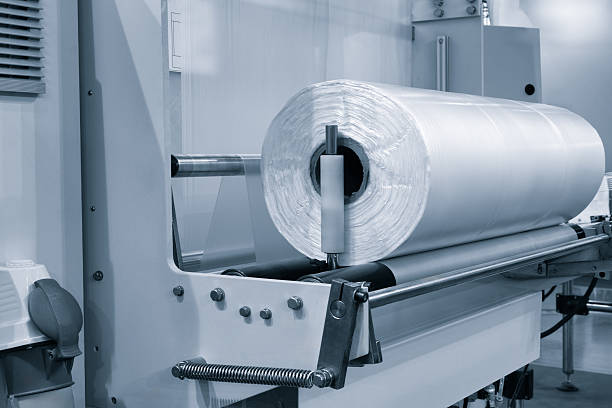 istock Automatic polyethylene plastic bag production machine with lighting effect. Close-up of the roller of the plastic bag production machine in the light blue scene. product packaging concept 2229456924