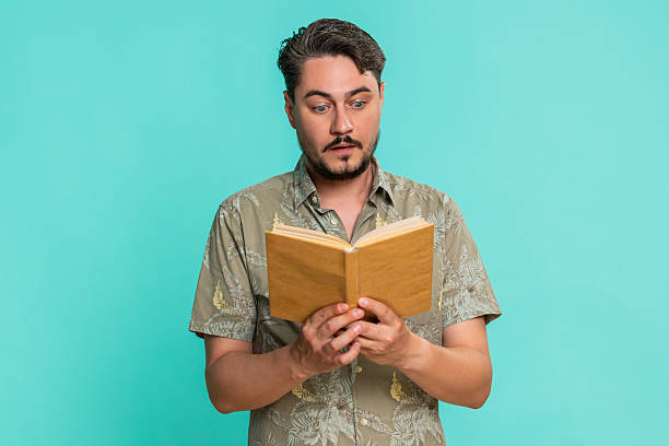 istock Man reading book with raised eyebrows showing surprise or interest in unexpected story twist moment 2229457417