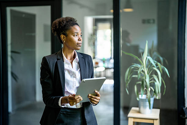 istock Businesswoman holding digital tablet looking through office window 2229457965