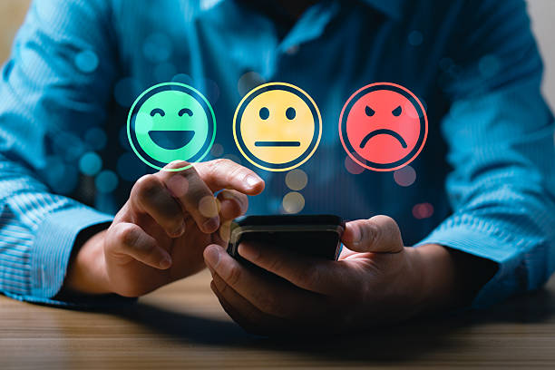 istock Customer satisfaction feedback concept showing person using mobile phone to select emotion face rating with happy, neutral, sad smiley icons representing service review and user experience evaluation 2229466577
