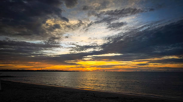 istock Golden sunset over beach with dramatic clouds and calm waves 2229468471
