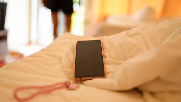 istock Smartphone rests on bed covered with white bedding, creating serene atmosphere. soft lighting enhances calmness of scene, inviting relaxation and comfort 2229469159
