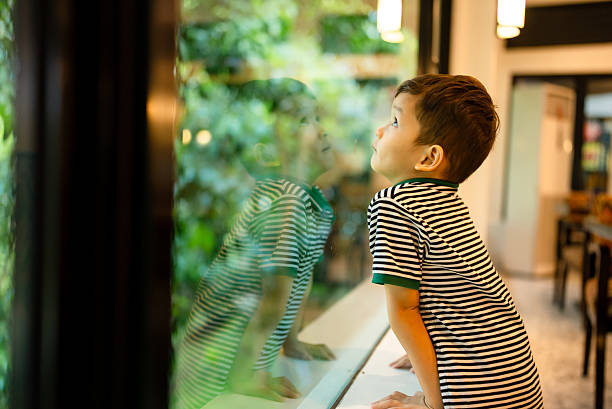 istock Excited boy looking out a window with raindrops 2229469698