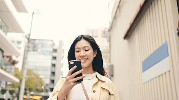 istock Japanese asian woman using digital tablet outdoors surrounded by green representing portable business tech and digital access  flexible business environments, and modern lifestyle technology. 2229472586