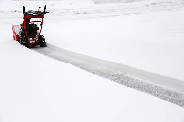 A man using a snowblower in a snowstorm.