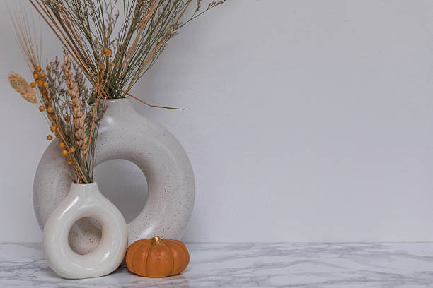 istock Modern Scandinavian-style decor with neutral ceramic vases, dried plants, and a tiny pumpkin on marble tabletop, creating an elegant autumn-inspired home atmosphere 2229477598