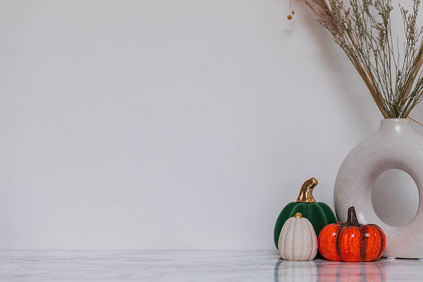 istock Stylish fall tabletop arrangement featuring circular ceramic vase with dried plants and decorative pumpkins, perfect for cozy seasonal, rustic, and Nordic interior design inspiration 2229477600