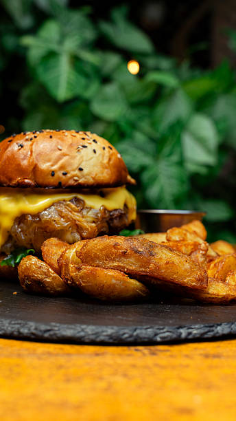 Delicious cheeseburger with fried potatoes and caramelized onions on slate plate
