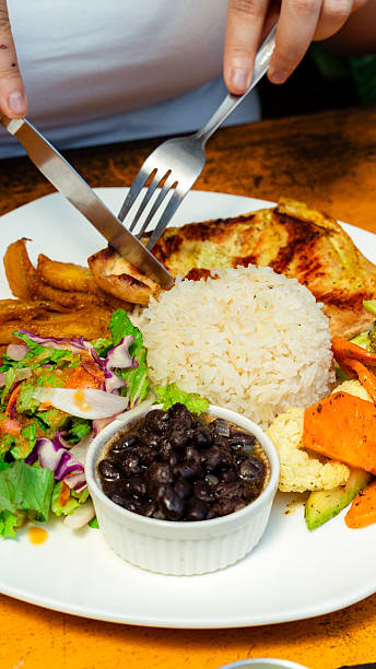 Close-up of a customer savoring bandeja paisa, a hearty colombian platter