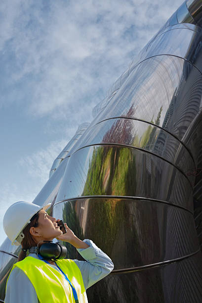 istock Female engineer using mobile phone while inspecting industrial air conditioning pipes 2229490493