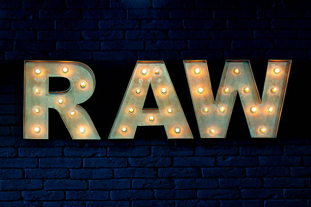 A lighted sign that says RAW on a brick wall