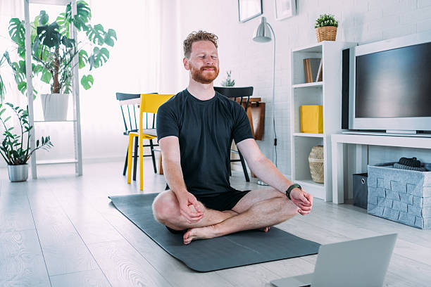 istock Young man meditating in Lotus position at home. 2229493648