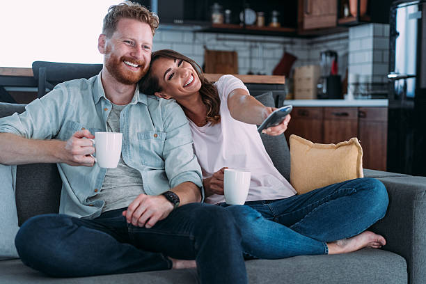 istock Cute young couple cuddling while watching tv. 2229493660