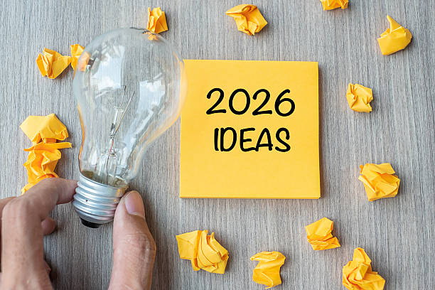 istock 2026 Idea words on yellow note and crumbled paper with Businessman holding lightbulb on wooden table background. New Year New Start Creative, Innovation, Imagination, Resolution and Goal concept 2229496579