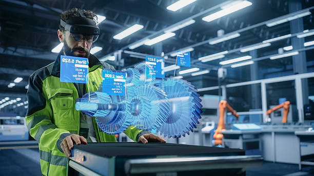 istock Automotive Factory Engineer Using Augmented Reality Headset in a Modern Facility with Automated Robotic Arms on an Assembly Plant. Specialist Ananlyzing and Manipulating a Virtual Gearbox Model 2229497826
