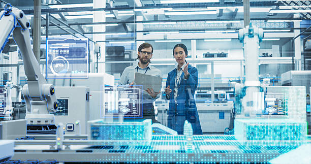 istock Electronics Factory Assembly Line Digitalization: Automated Robot Arms Manufacturing Advanced Equipment. Managers Discussing Work while Futuristic AI Computer Vision Analyzing, Scanning Conveyor Line 2229498909