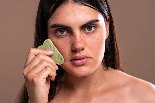 istock Young woman using gua sha stone for face massage and skincare routine 2229502592