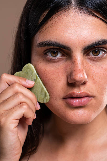 istock Beautiful young woman using gua sha stone for face massage 2229503230