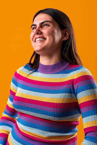 istock Young woman smiling and looking up on orange background 2229503420