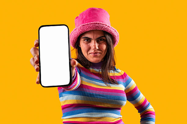 istock Young woman showing smartphone screen on orange background 2229503486