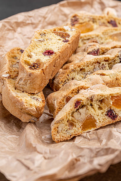 Italian Almond Biscotti biscuits in a rustic home made pottery bowl. Studded with almonds and cranberries, these twice-baked treats are aromatic and inviting. Ideal.