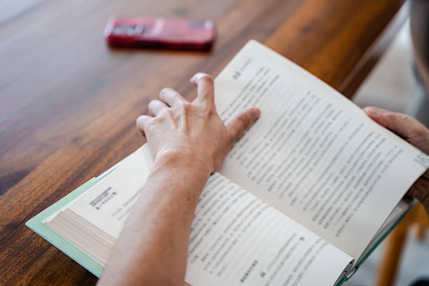 A person leads a finger on the lines in the book, but instead of letters only question marks on the page in the textbook.