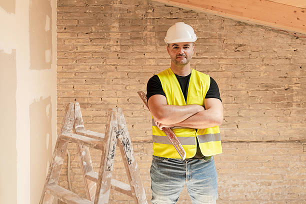 istock Male Construction worker in safety hardhat posing with level tool and crossed arms at building site 2229518418