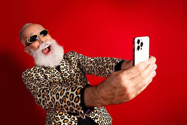 istock Charismatic elderly man in leopard print suit taking a selfie against a vibrant red backdrop showcasing his eccentric personality 2229521737