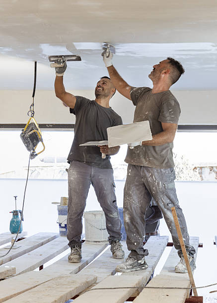 istock Two men working standing on scaffoldings, use trowel and hawk to plaster ceiling, construction 2229522220