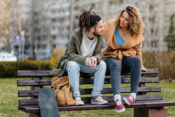 istock Young Couple Sitting On A Park Bench 2229525133