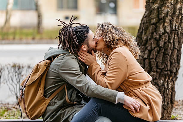 istock Young Couple Kissing While Sitting On A Park Bench 2229525452