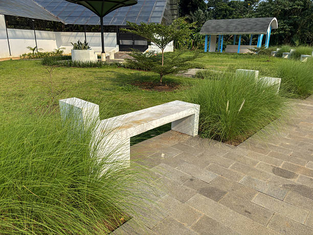 istock modern white bench in a park surrounded by green grass and landscaping. 2229526375