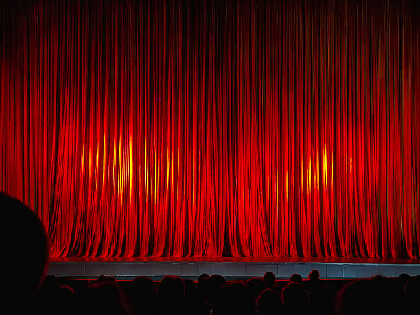 istock Red theater curtains on stage with spotlight shining before stage performance begins. Background. Concept of anticipation, performing arts, cultural entertainment 2229529112