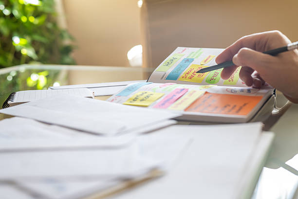 istock Person is carefully checking and planning their schedule in a notebook filled with colorful sticky notes, meticulously organizing work or personal agenda at home 2229530465