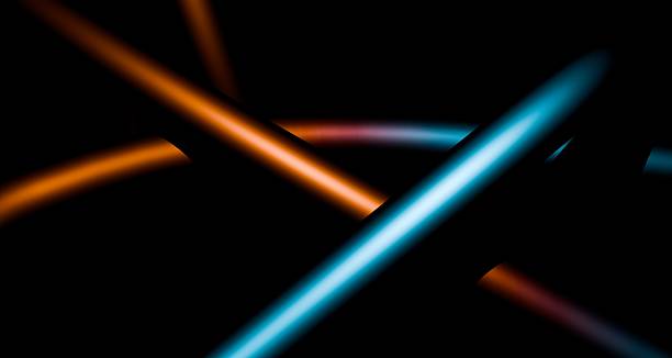 istock Curved orange and blue light trails intersect against a black background. 2229531251