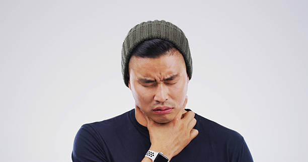 istock Allergy, hurt or Asian man with sore throat on studio space for cold, flu or virus symptoms. Choke, sick or male person isolated on white background with neck pain, thyroid inflammation or asthma 2229534363
