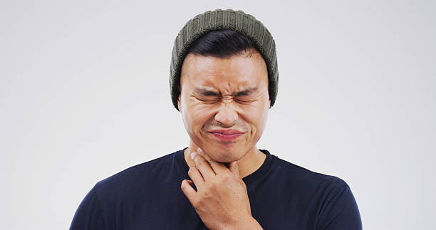 istock Allergy, hurt and man with sore throat on studio space for cold, flu or virus symptoms. Asthma, bacteria or Asian person isolated on white background with neck pain, thyroid inflammation or injury 2229534370