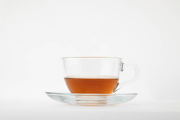 istock A clear glass teacup filled with amber-colored tea, possibly black or rooibos, resting on a matching clear glass saucer 2229534809